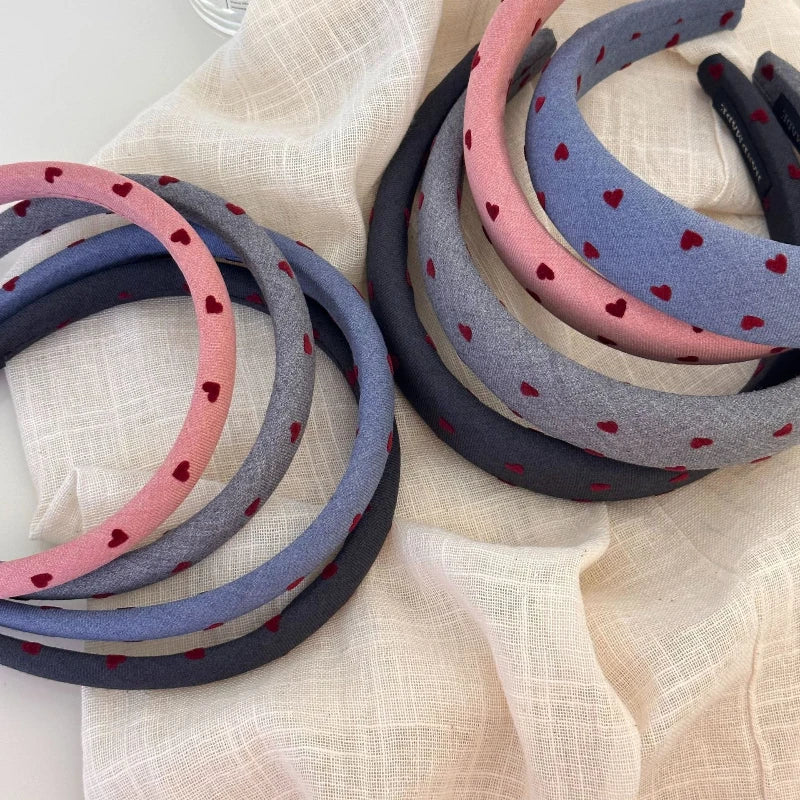 Set of hairbands with heart patterns in pink, blue, and gray on a light fabric background