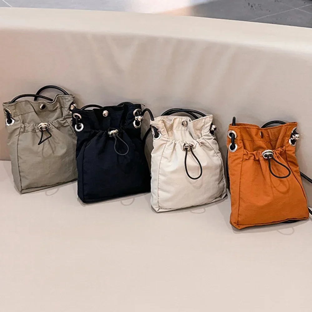 Four drawstring bags in gray, black, white, and orange on a light surface.