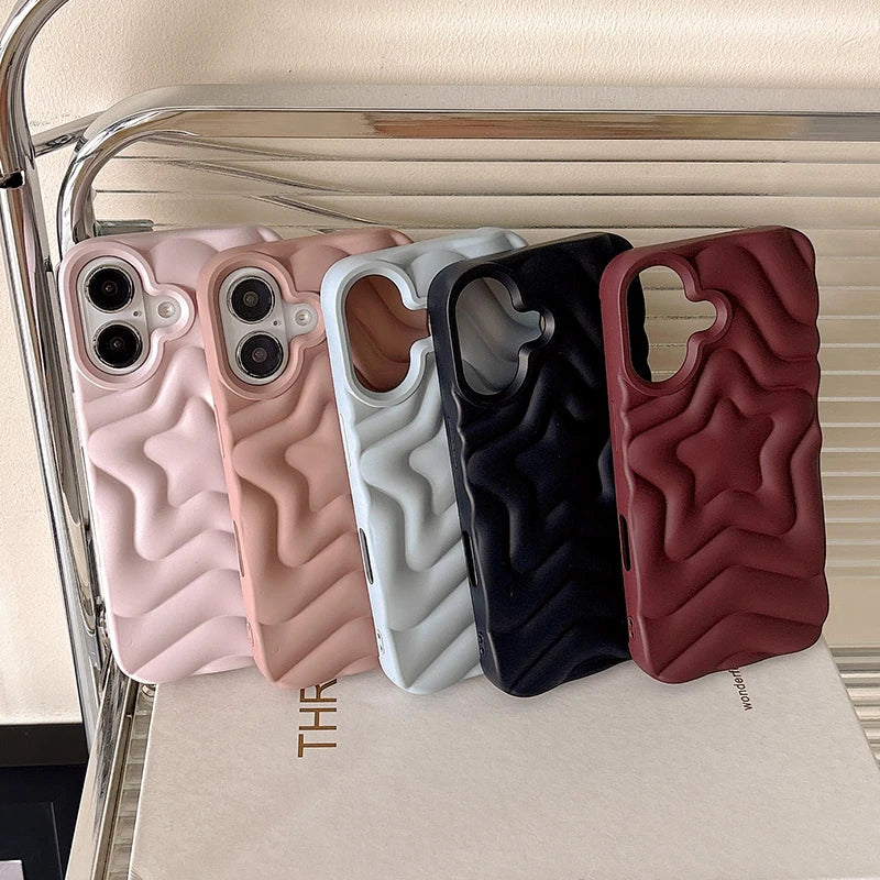 Four phone cases in pink, white, black, and red on a stand with a brand name visible.