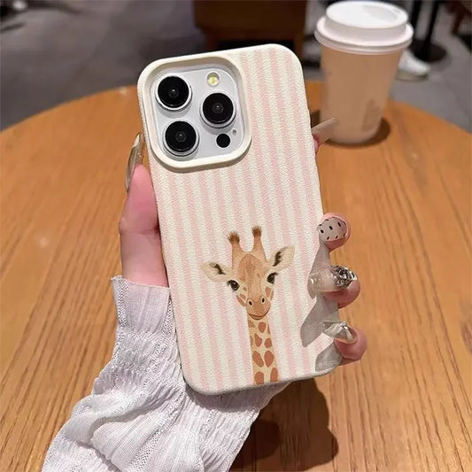 Phone case with a giraffe design held by a hand on a wooden table.