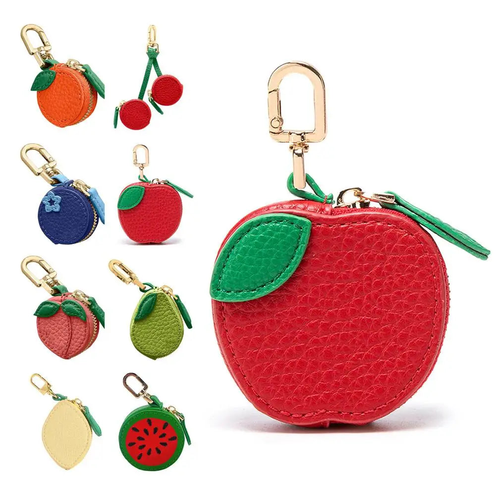 Collection of fruit-themed keychains and a red apple-shaped pouch on a white background