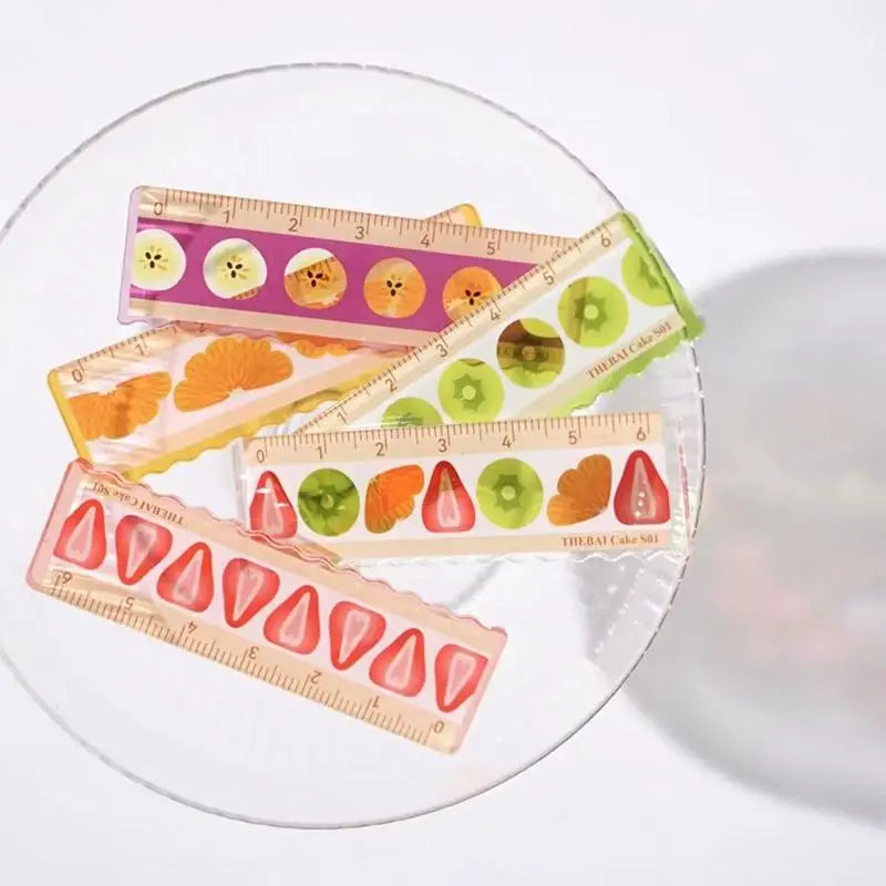 Four transparent rulers with fruit pattern on a white plate