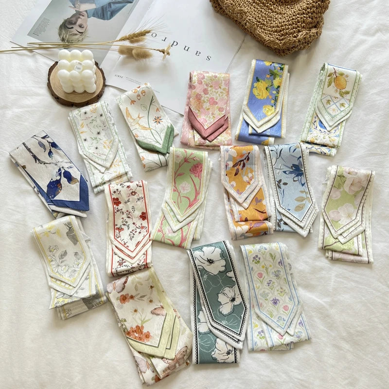Collection of floral handkerchiefs on a magazine with a straw hat and decorative items.