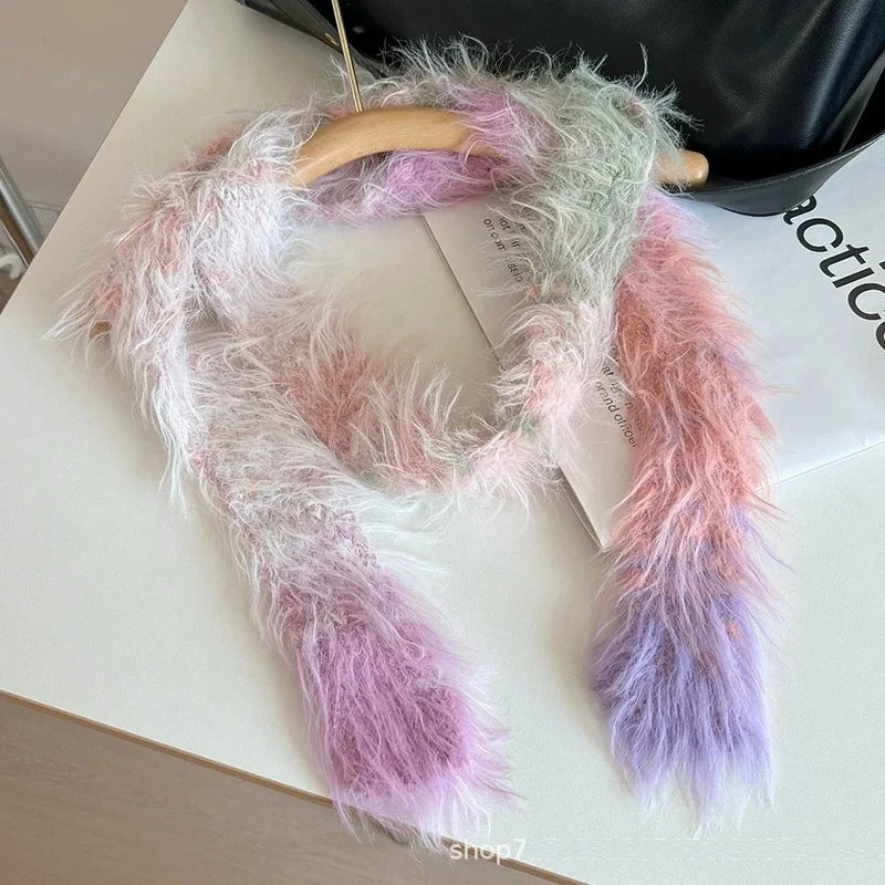 A fluffy faux-fur scarf in pastel pink, lavender, and mint green tones, draped over a wooden hanger on a white tabletop with a black bag in the background.