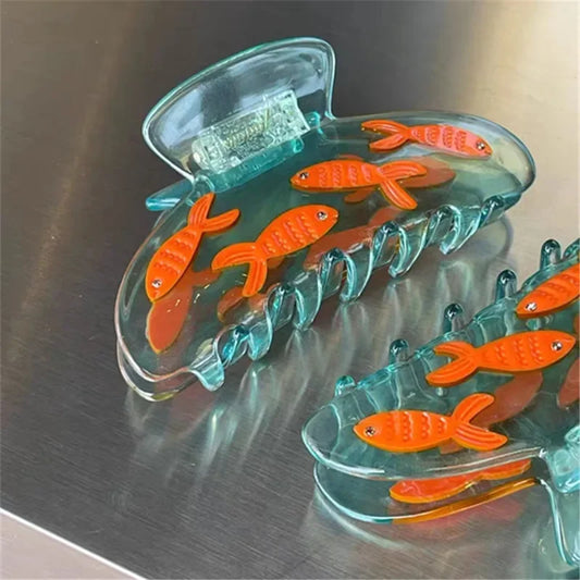 Clear plastic clips with orange fish designs on a metallic surface