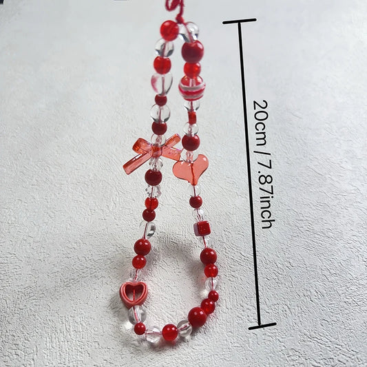 Red and clear acrylic bead phone strap with heart and bow charms, shown on a light textured background with a black measurement line indicating 20cm (7.87 inches) length.