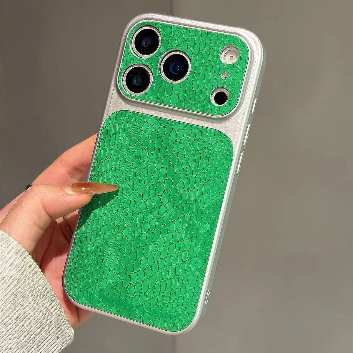 A hand holding a smartphone case with a bright green textured back panel and matching camera surround, shown against a plain gray background.