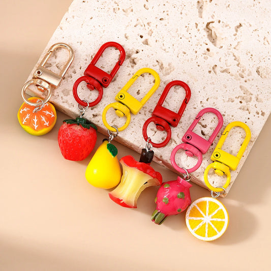 Colorful fruit-shaped keychains on a textured surface