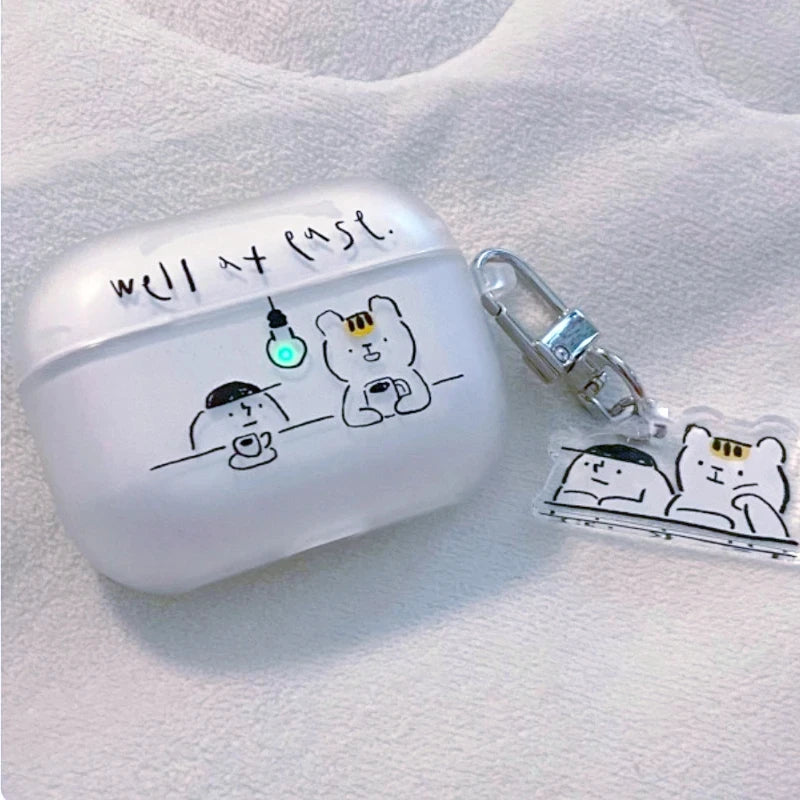 A frosted white AirPods case with a cute cartoon bear and cup illustration, featuring the handwritten text 'WELL AT Ease.' on top.