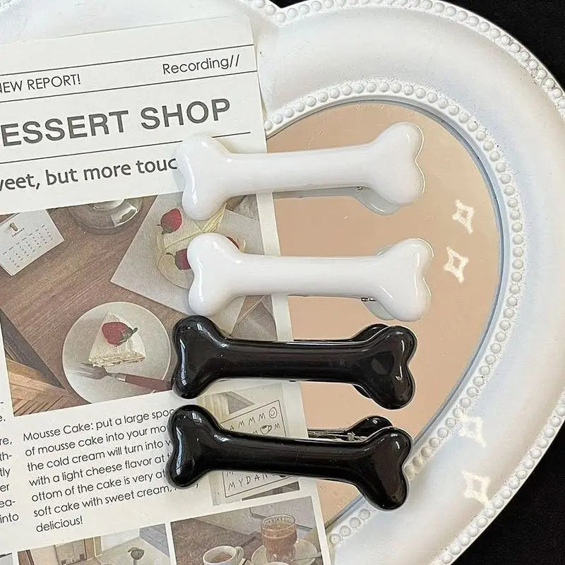 White and black bone-shaped hairclips on a decorative plate with a newspaper background