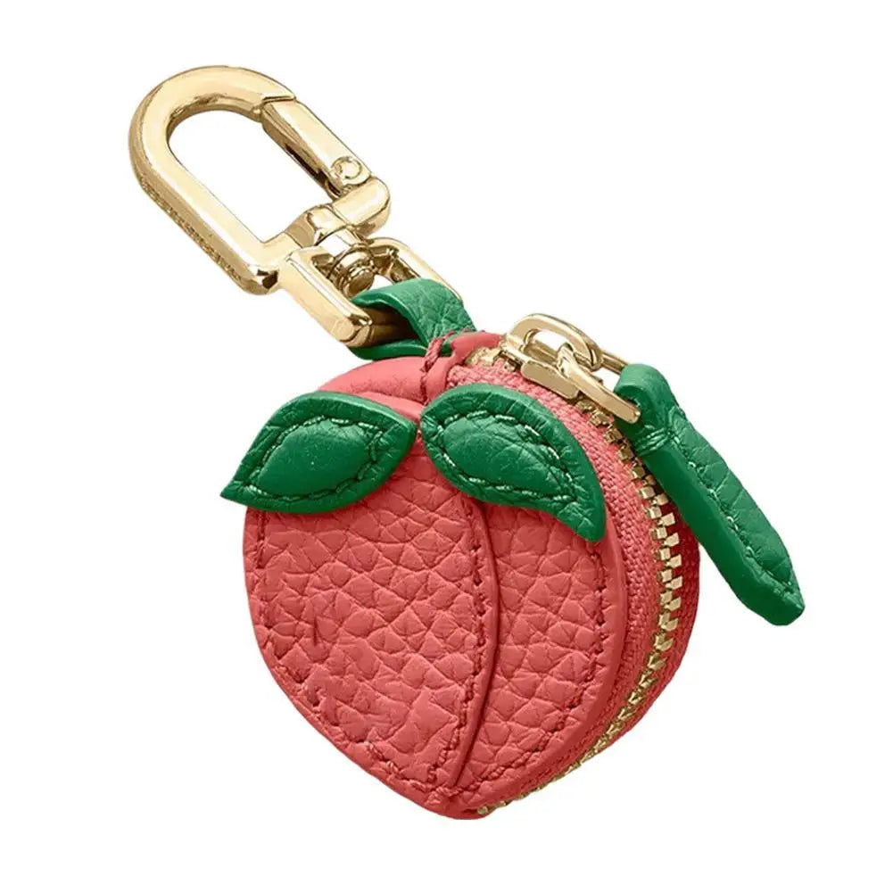 Pink peach-shaped keychain with green leaves and gold carabiner on a white background