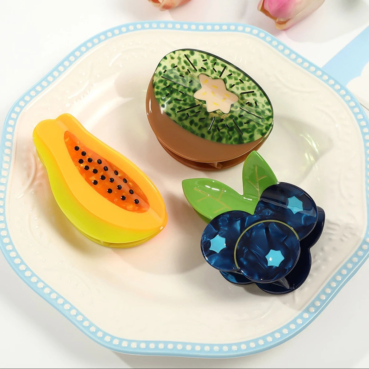 Fruit-themed hair clips on a white plate with blue rim
