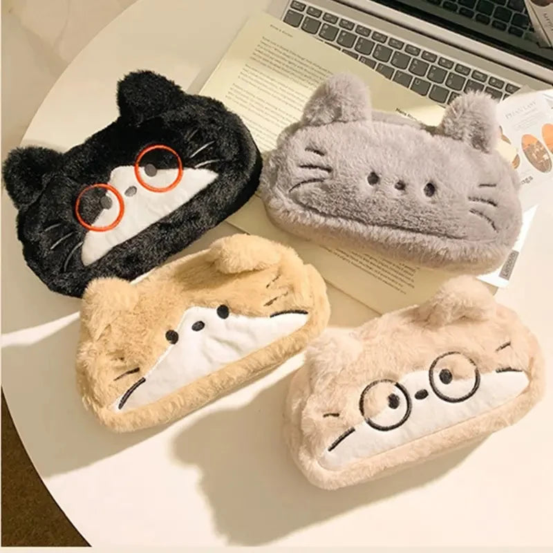 Four cartoon-style plush pencil cases with cat faces on a desk.
