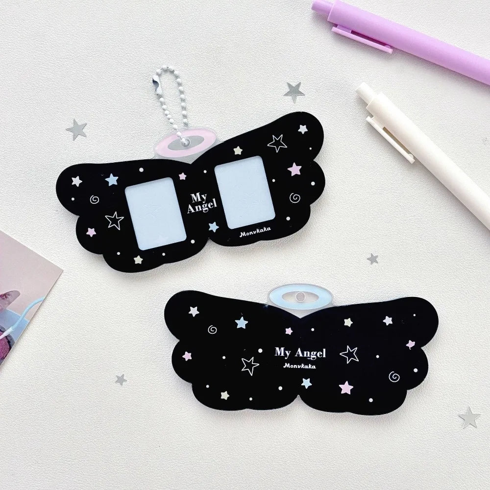 Black butterfly-shaped photo frames with 'My Angel' text on a light surface with pens and stars.