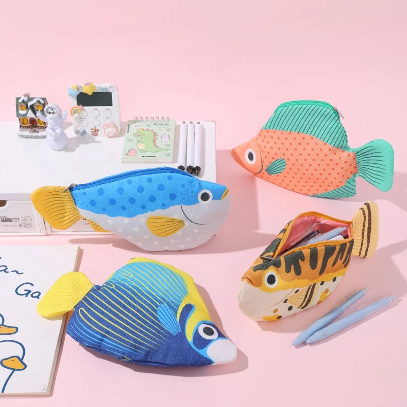 Fish-shaped pencil cases on a pink background with stationery items.