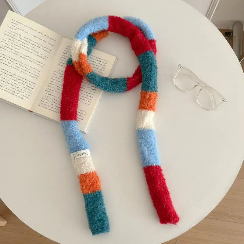 Colorful striped scarf on a white surface with glasses and an open book.