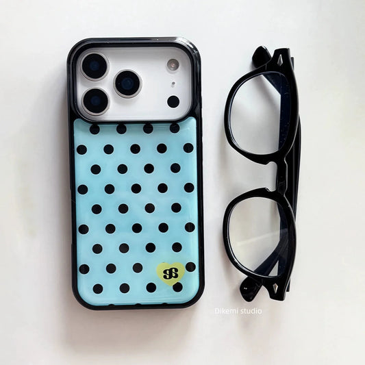 A light blue phone case with black polka dots and a small yellow dollar-sign logo, shown next to a pair of black eyeglasses on a white background.