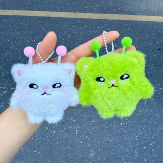 Two fluffy keychains, one blue and one green, held against a dark background.