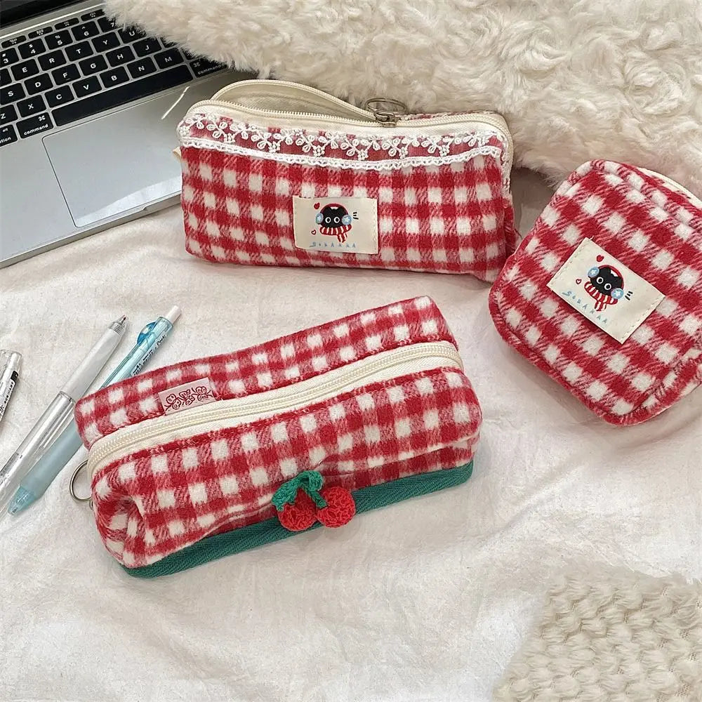 Red and white checkered pencil cases with a small red flower on a white surface.