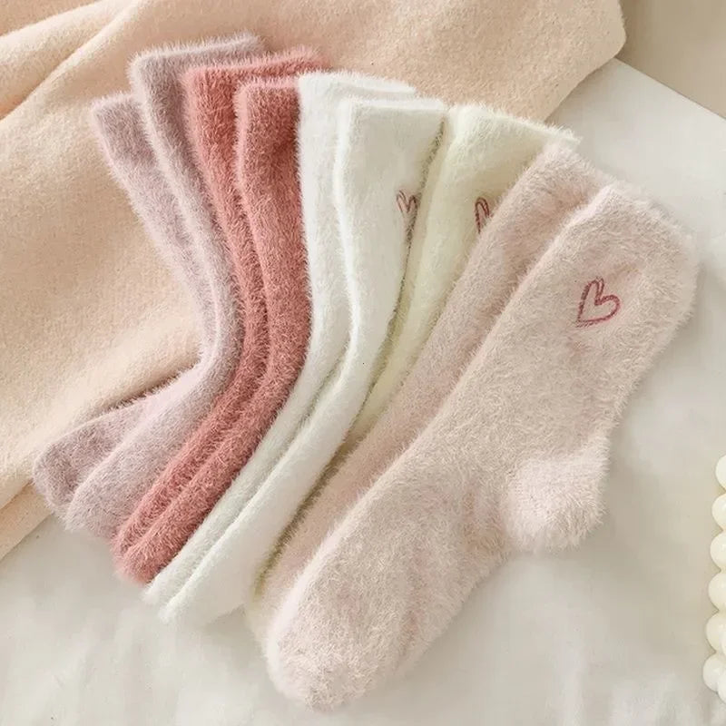 Set of fluffy socks with heart designs in various shades of pink and white.
