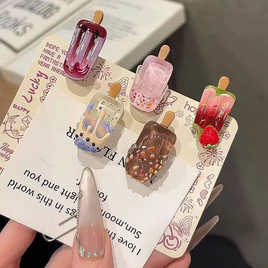 Set of ice cream-themed hair clips on a decorative card held by a hand.