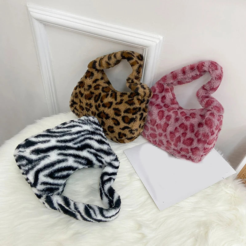 Three faux fur handbags with leopard, zebra, and pink patterns on a white surface.