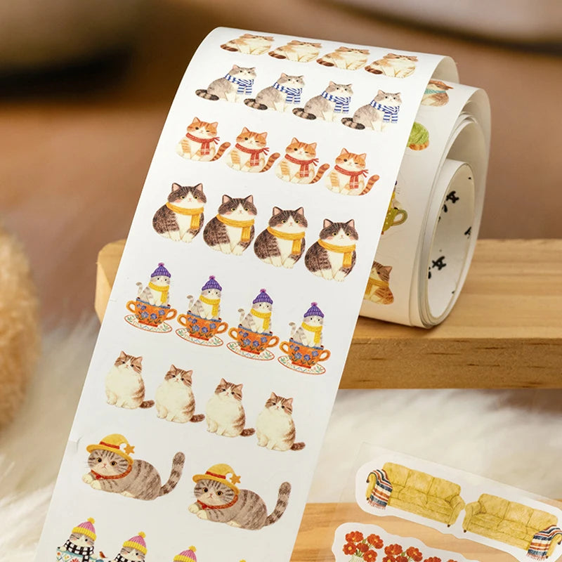 Roll of stickers with cartoon cats in various outfits on a wooden surface.