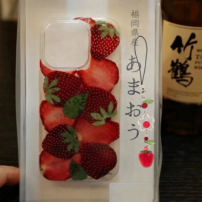 A clear phone case printed with a strawberry pattern, shown inside its white retail packaging. The packaging features Japanese text and a small illustration of a strawberry.