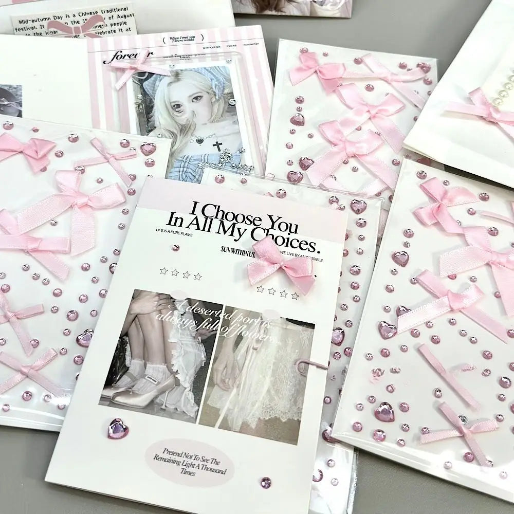 A collection of pink and white stationery items, including envelopes, cards, and decorative sheets, embellished with pink satin bows, clear rhinestones, and heart-shaped gems. One card prominently displays the text 'I Choose You In All My Choices.