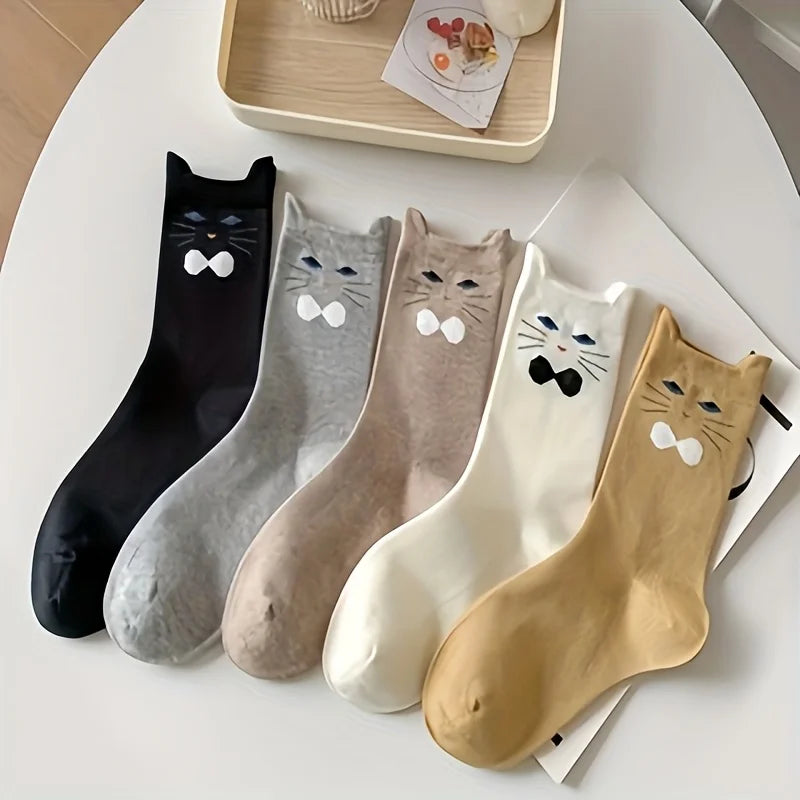 Set of five cat-themed socks in black, gray, brown, white, and beige on a white surface.
