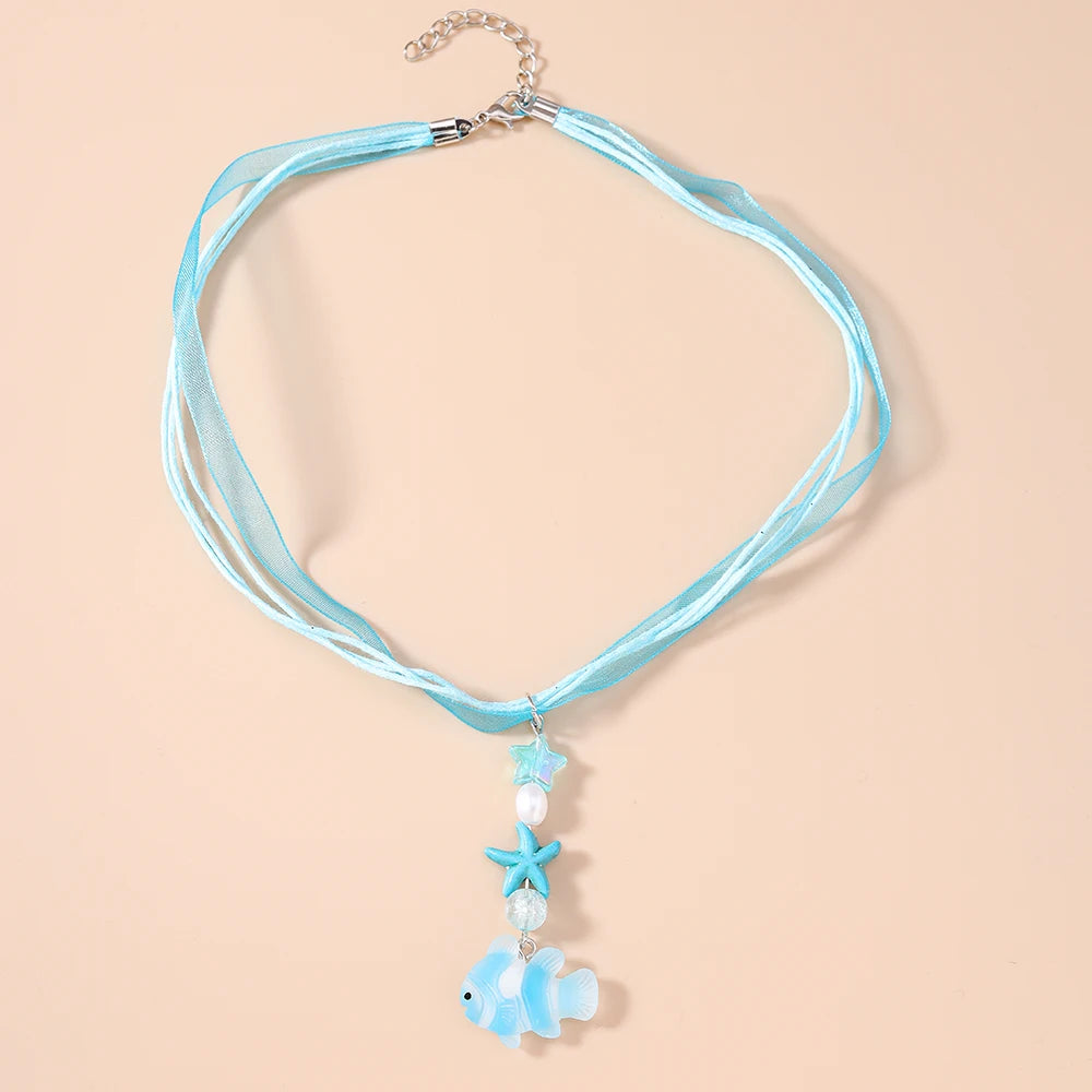 Necklace with blue ribbons and starfish pendants on a beige background