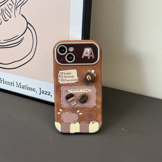 A brown phone case with a coffee-themed illustration, featuring a recipe card design with coffee beans and a small 3D coffee cup charm, displayed on a dark surface next to a framed print.