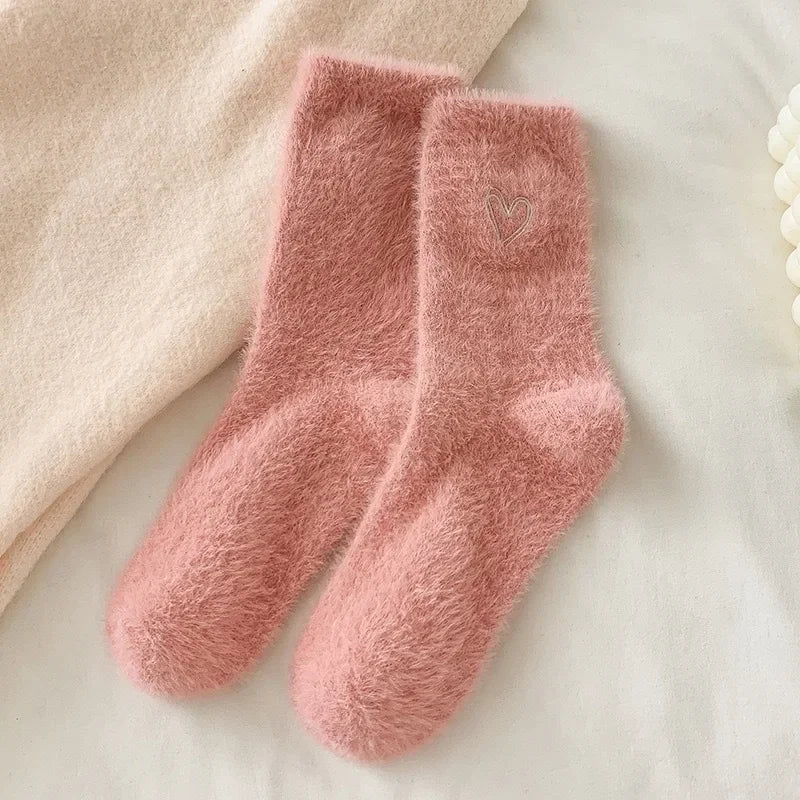 Pair of pink fuzzy socks on a soft surface