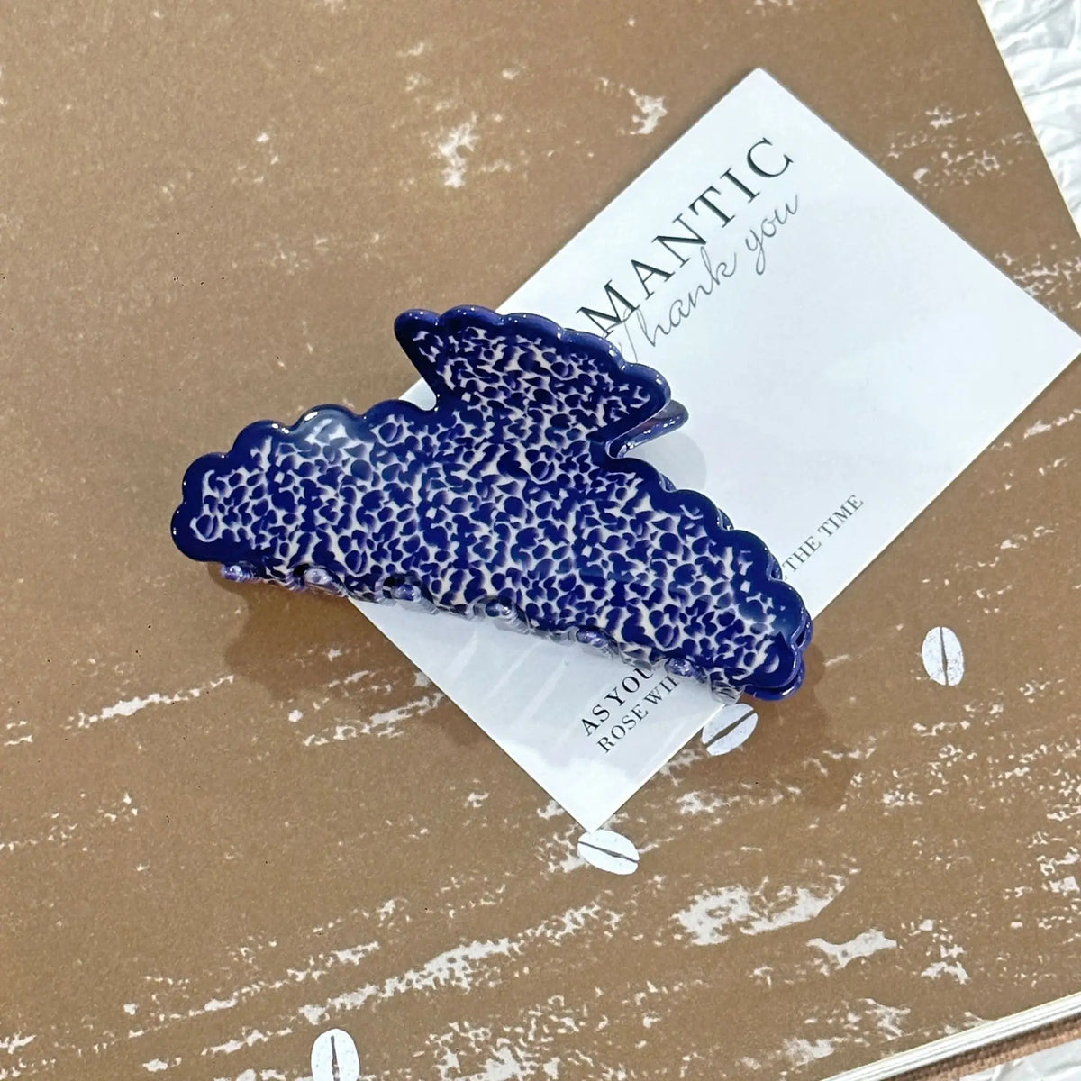 Blue textured hair clip on a brown surface with a card underneath