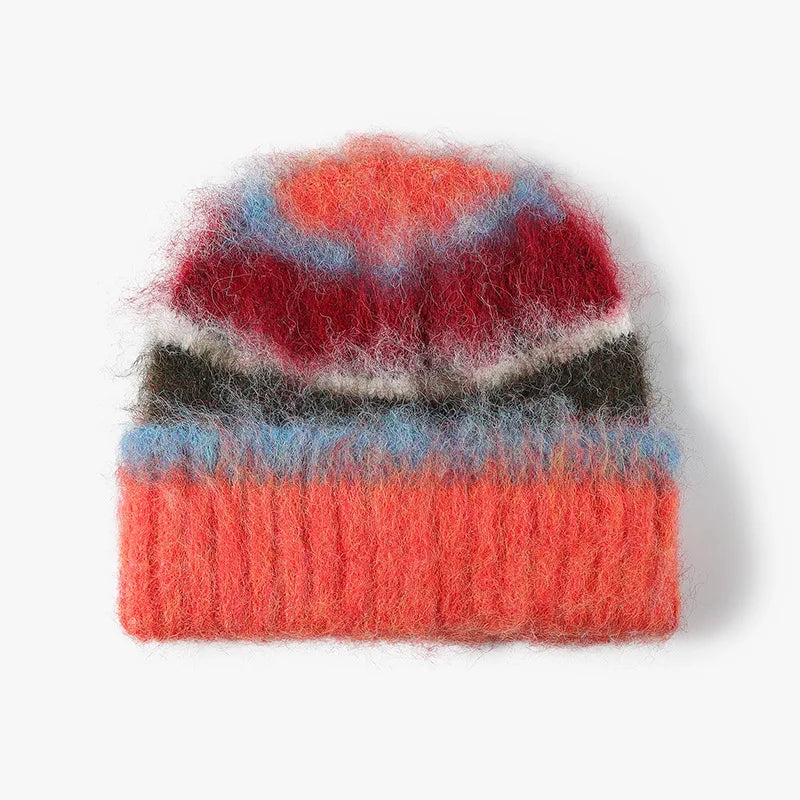 A fuzzy, hand-dyed knit beanie hat featuring a multicolor pattern of coral, red, light blue, dark gray, and off-white stripes, shown against a plain white background.