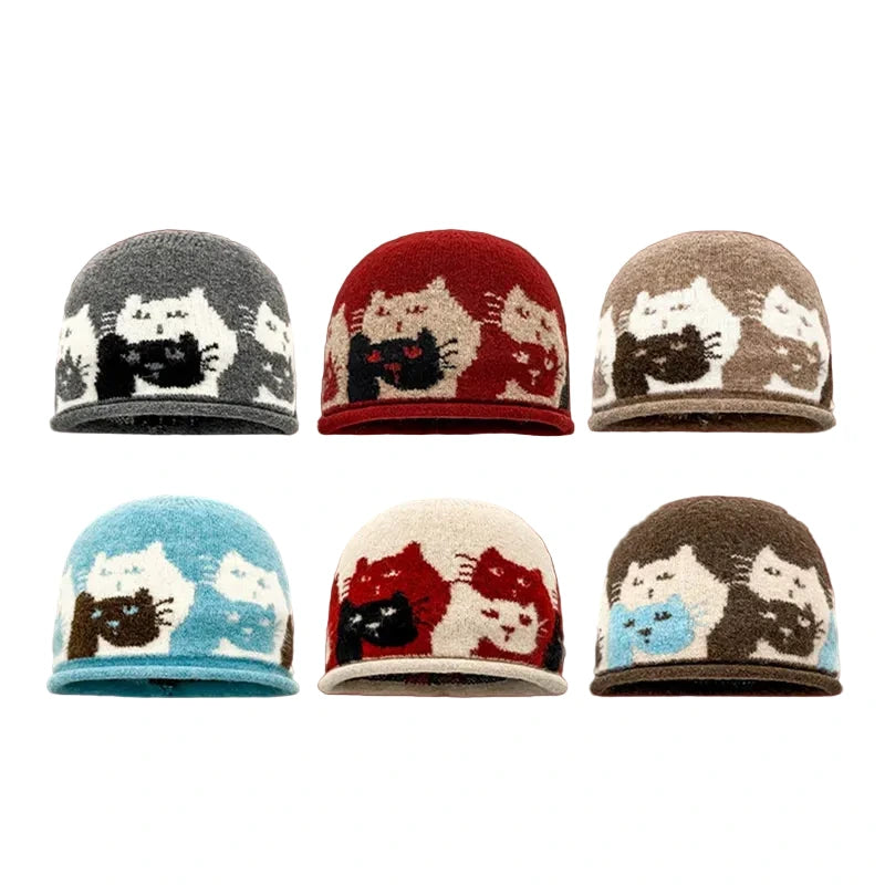Six knitted beanies arranged in a 2x3 grid on a white background, each featuring a repeating cat pattern in different colorways: gray/white/black, red/cream/black, taupe/white/brown, light blue/cream/brown, cream/red/black, and brown/blue/cream.