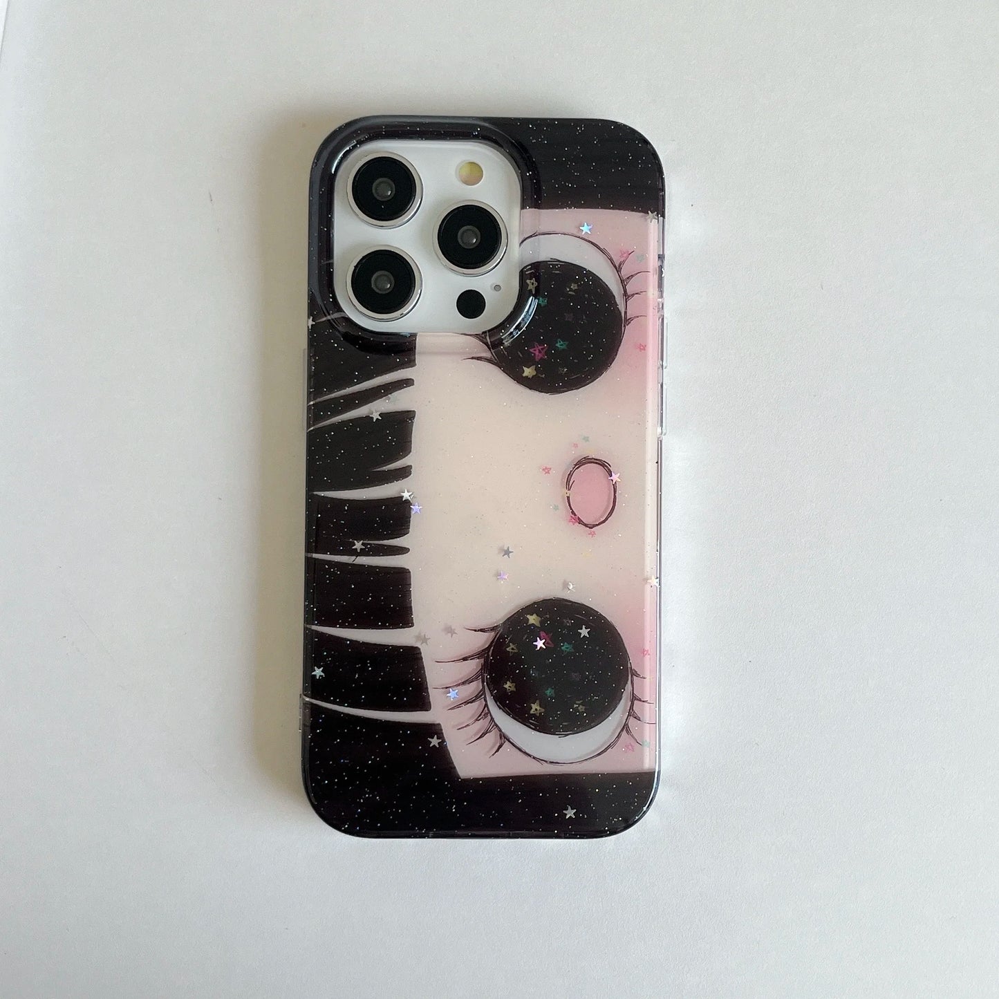 Phone case with eye design and starry background on a white surface