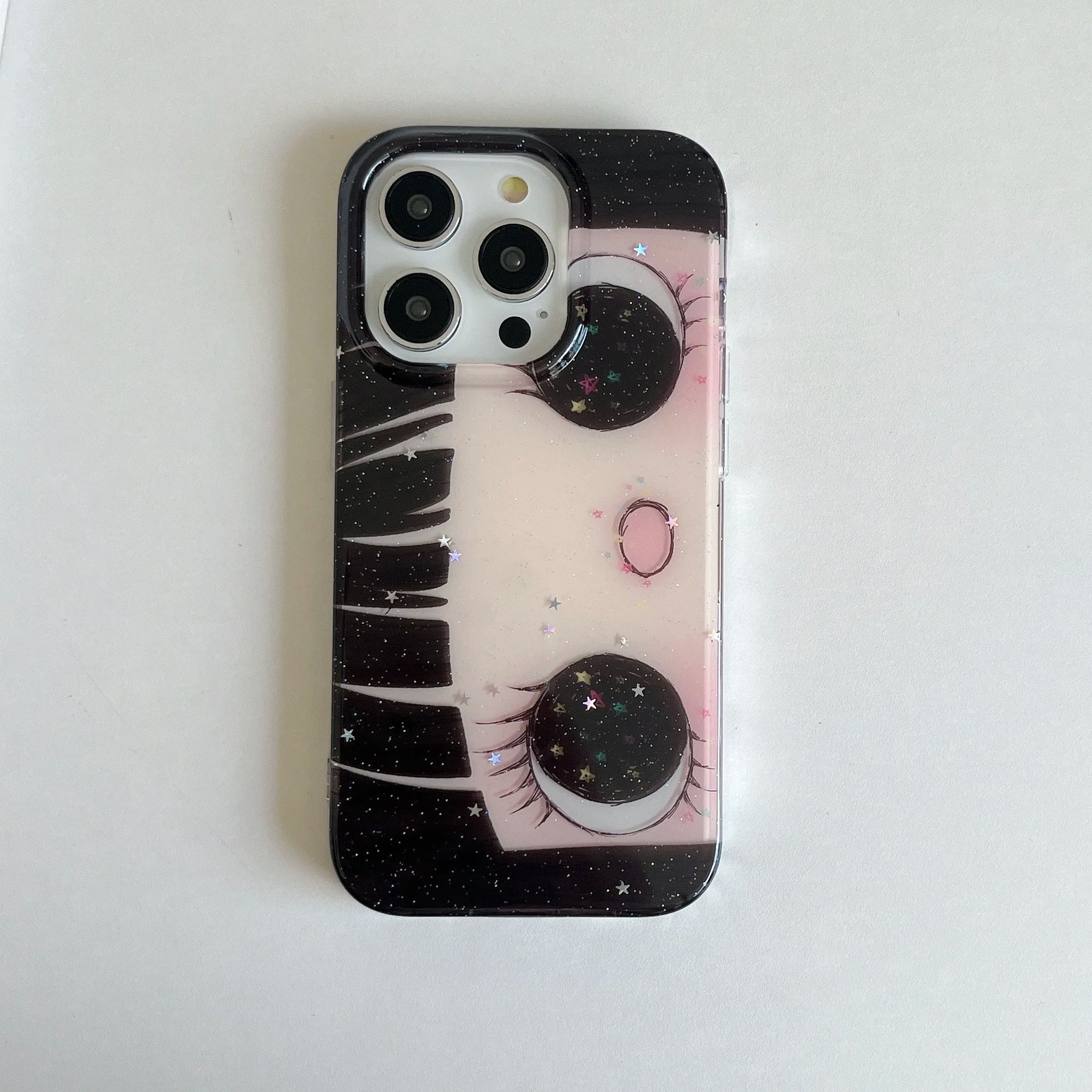 Phone case with eye design and starry background on a white surface