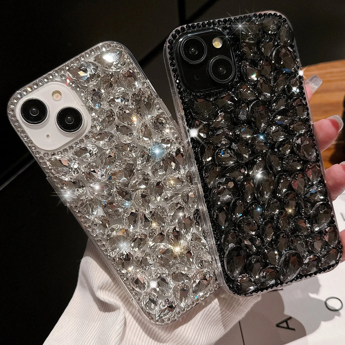 Two phone cases, one silver and one black, with sparkling rhinestone designs.
