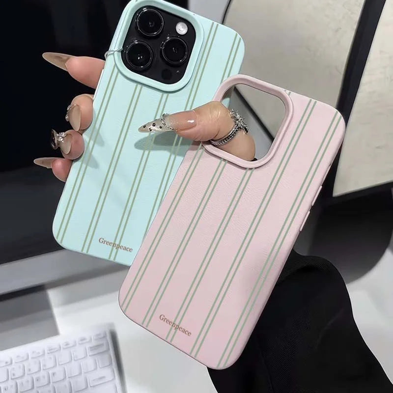 Two phone cases with green stripes held by a hand, one light blue and one pink.