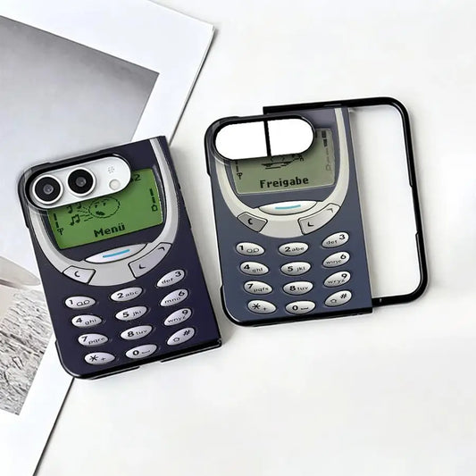 Two retro-style phone-shaped phone cases displayed on a white surface, one with a dark navy case and one with a black frame around a gray and navy design, styled with a white photo print in the background.