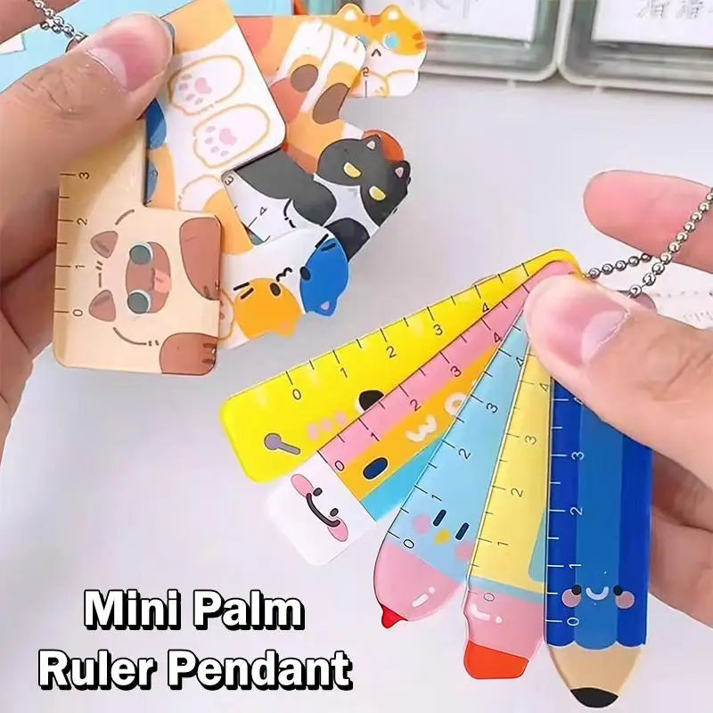 Mini palm ruler pendants with cartoon designs held by a hand on a light background.