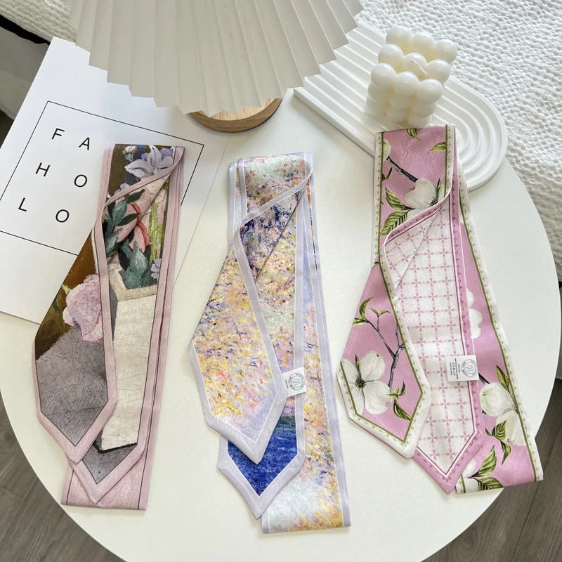 Three decorative neckties arranged on a white round table. The left tie is pink with floral and abstract botanical prints; the middle tie has a pastel floral pattern with iridescent shimmer and a blue section near the bottom; the right tie is pink with white floral motifs, green leaves, and a subtle grid pattern.