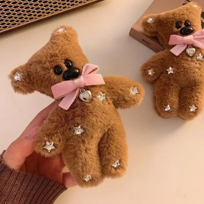 Small brown teddy bear with a pink bow held by a hand on a light background