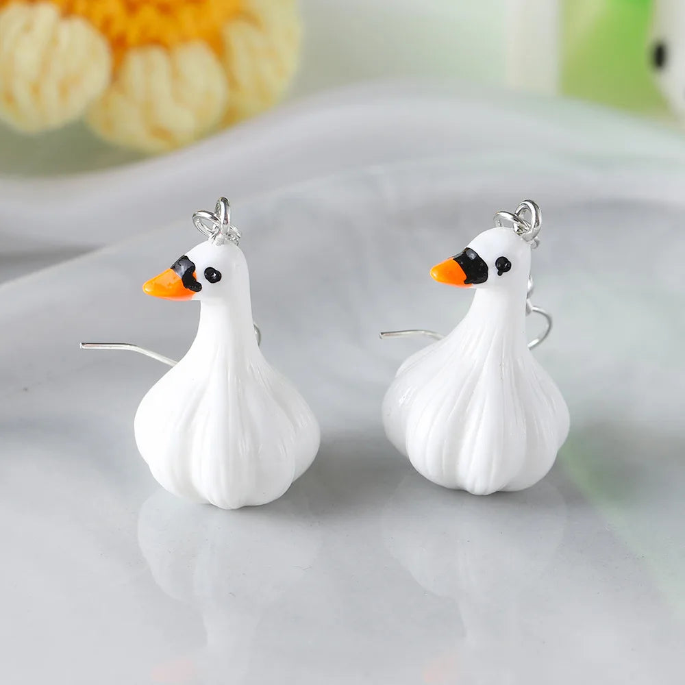 White swan-shaped earrings with orange beaks on a light gray background
