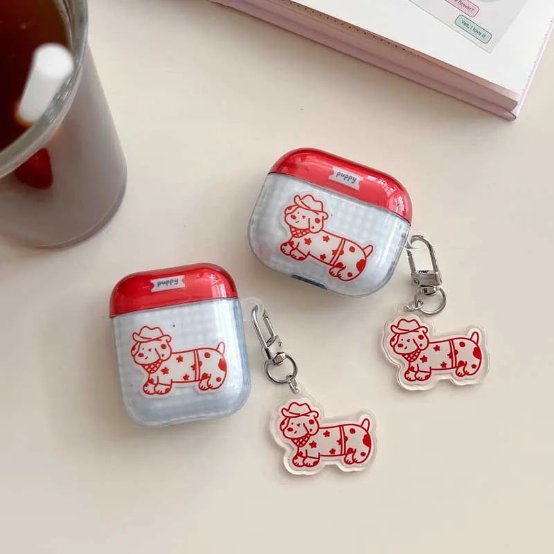 Red and white dog-themed air pod cases with matching keychain and charm on a light surface.