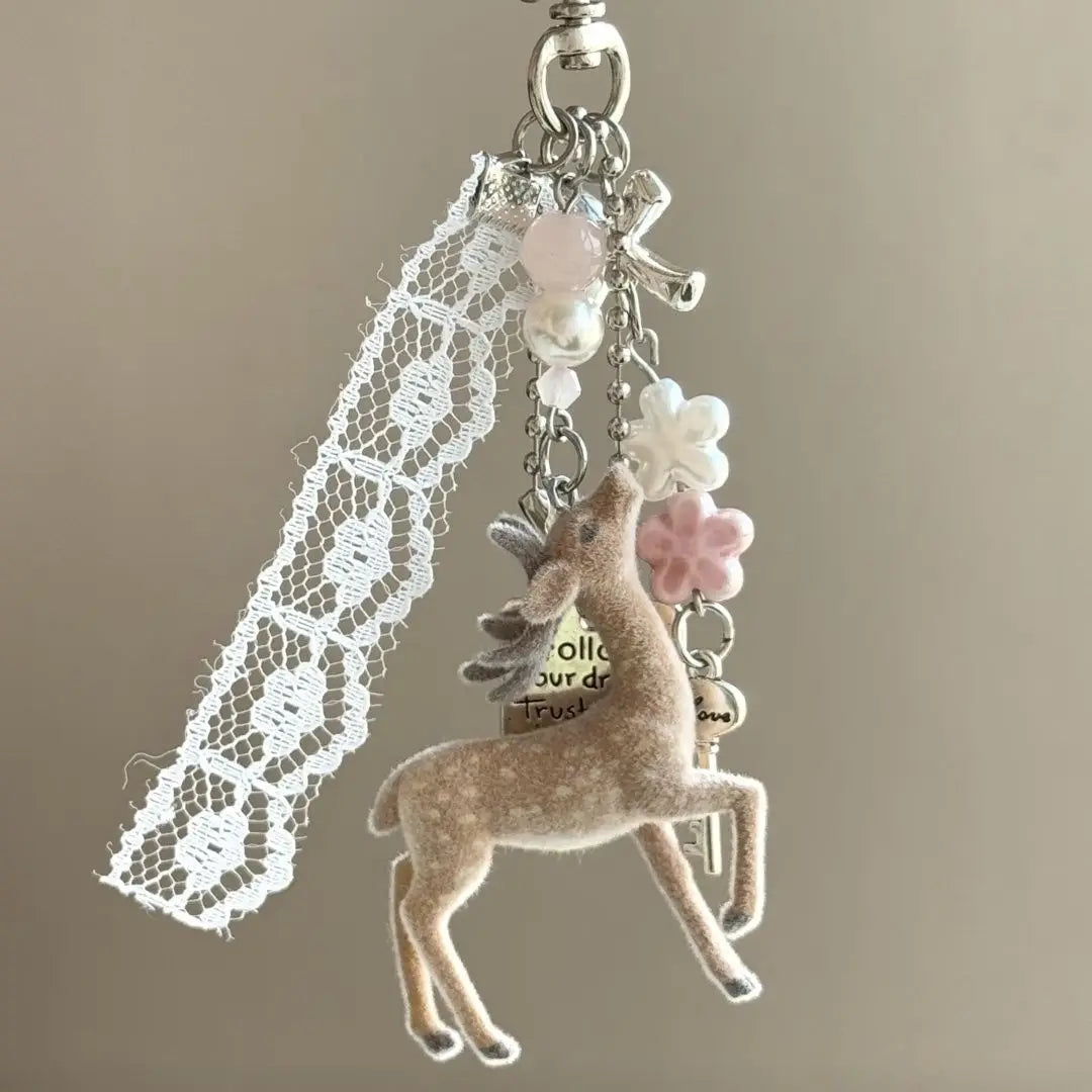 Decorative keychain with lace, deer charm, and flowers on a beige background