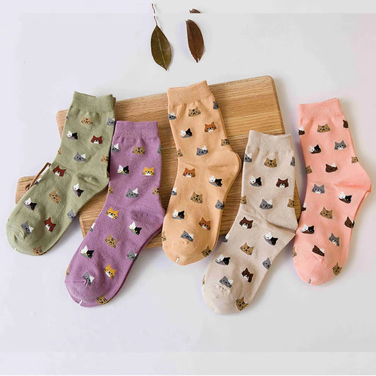 Five pairs of socks with cat patterns on a wooden board.