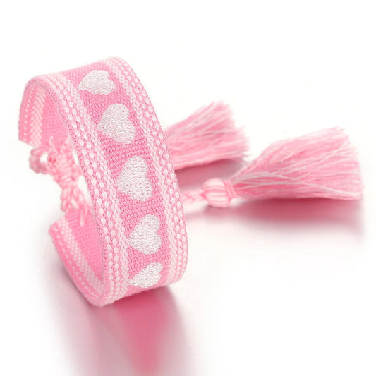 Pink ribbon with white heart patterns and tassels on a white background