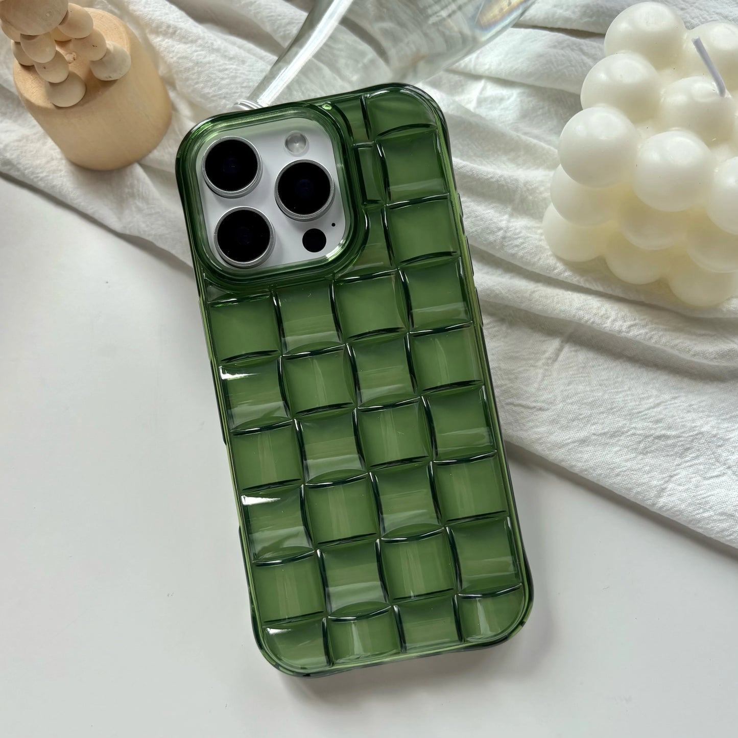 Green checkered phone case on a white surface with decorative items.